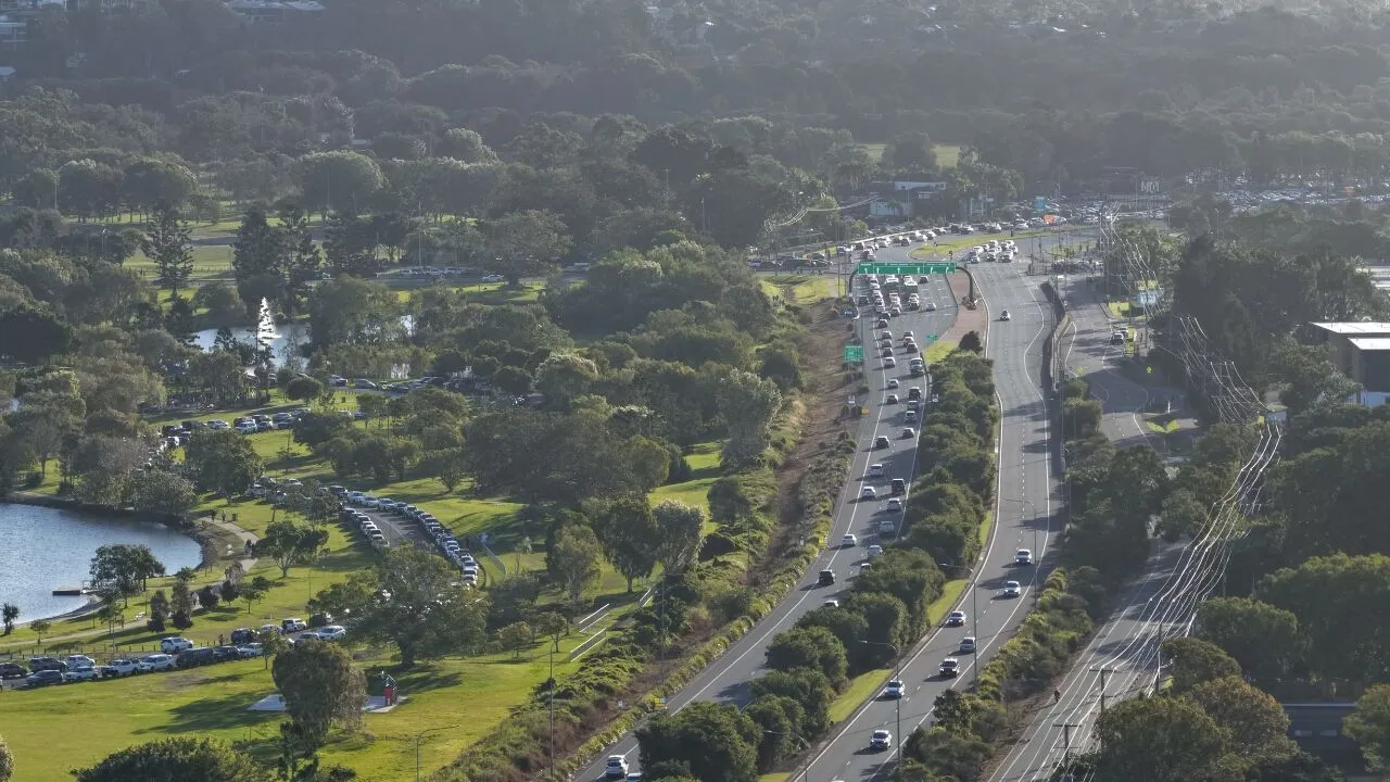 An aerial view of a South East Queensland highway running beside parkland and water
