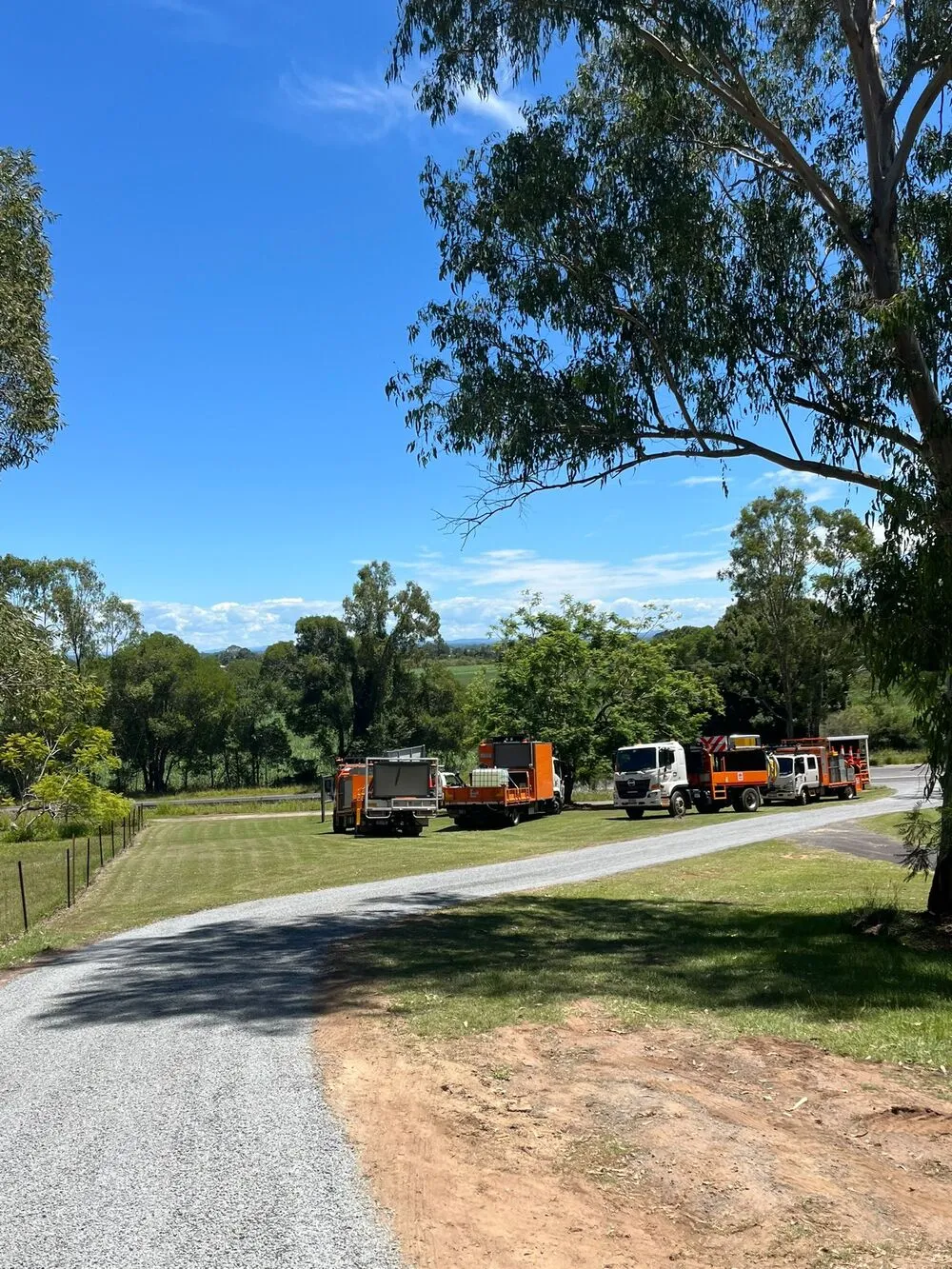 A fleet of service vehicles parked on a driveway at a rural property