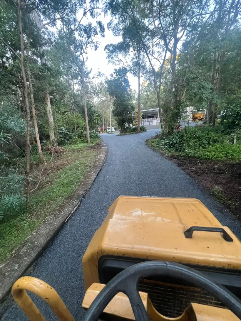 A tree-lined driveway running down to a home surrounded by bushland