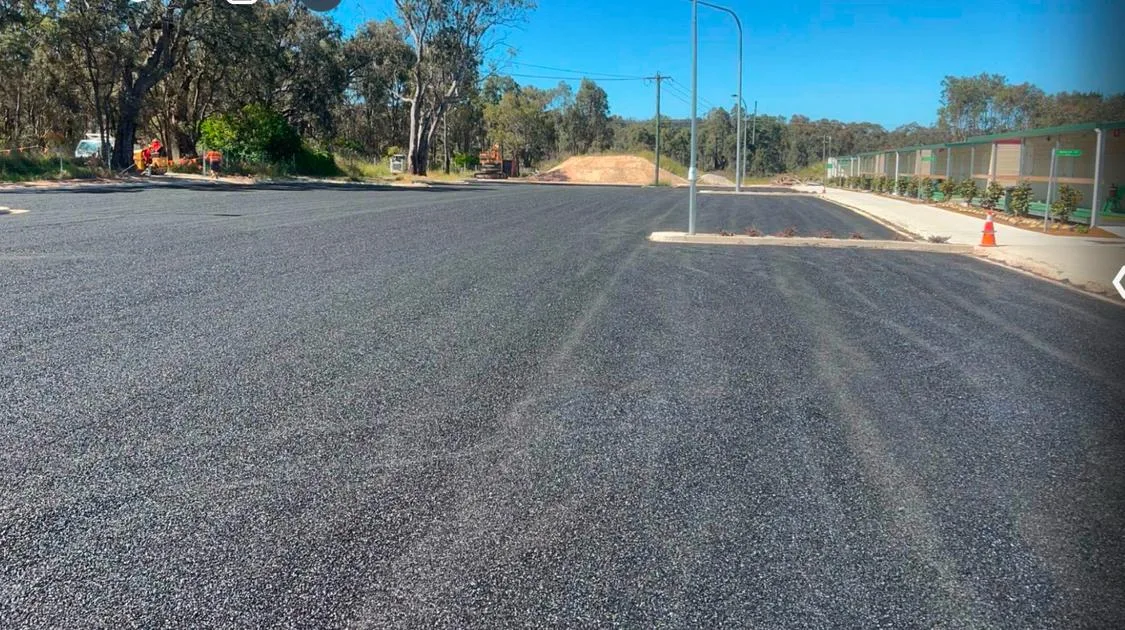 Newly laid asphalt surface with kerbing, street lighting and a traffic cone