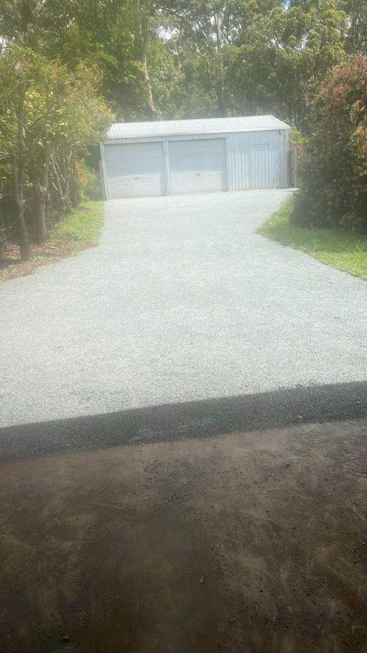 A freshly spray sealed driveway leading to a shed on a rural property
