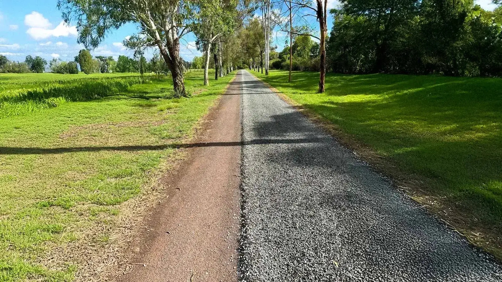 A rural South East Queensland driveway with a freshly laid asphalt strip beside the old gravel